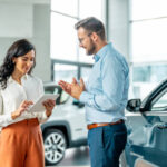 man presents customer car showing characteristics on tablet